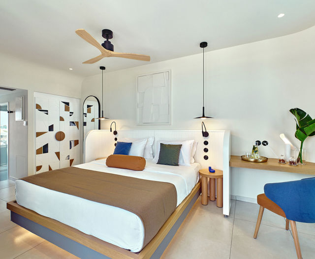 Cozy Kosta Alimia room with double bed, ceiling fan, hanging lights, desk, chair, and colorful geometric wall tiles