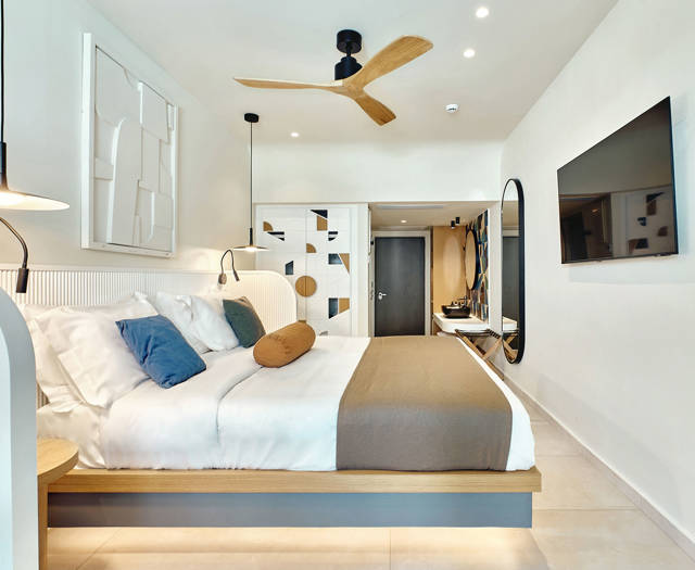 Swim-up room with king-size bed, ceiling fan, flat-screen TV, and view toward the entrance and bathroom.