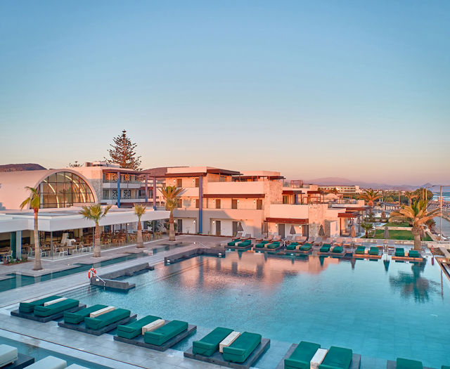 Large outdoor pool surrounded by sunbeds and modern buildings at Kosta Alimia hotel.