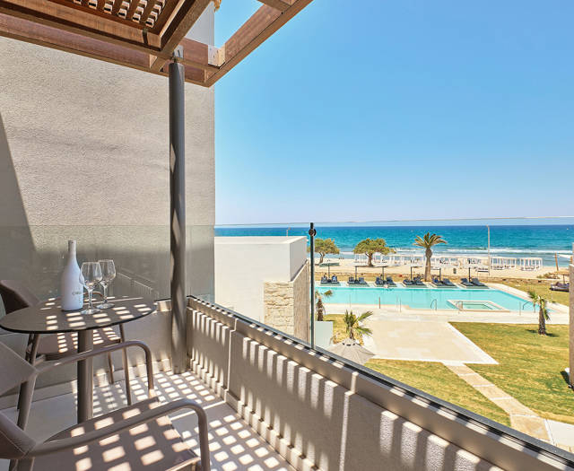 Junior suite's private balcony with two chairs and a table having a side sea view