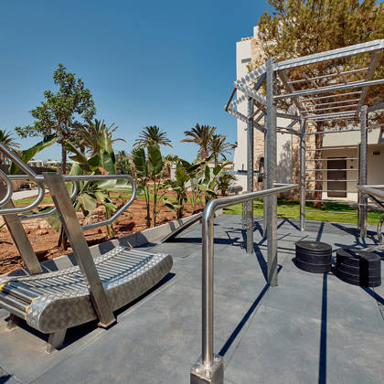 Outdoor gym area with modern stainless steel workout equipment under clear blue skies.