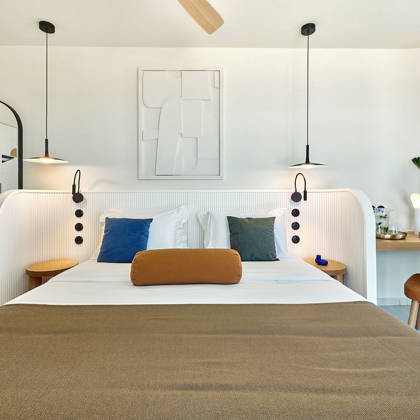 Bright retreat bedroom with modern furnishings, colorful pillows, and a minimalist wall design.