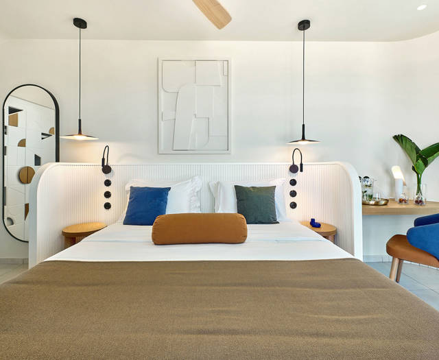 Bright retreat bedroom with modern furnishings, colorful pillows, and a minimalist wall design.
