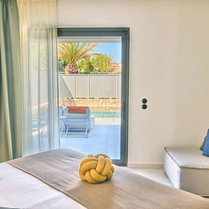 Suite bedroom with a corner desk, a sofa and direct access to the private pool