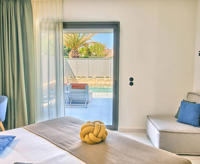 Suite bedroom with a corner desk, a sofa and direct access to the private pool