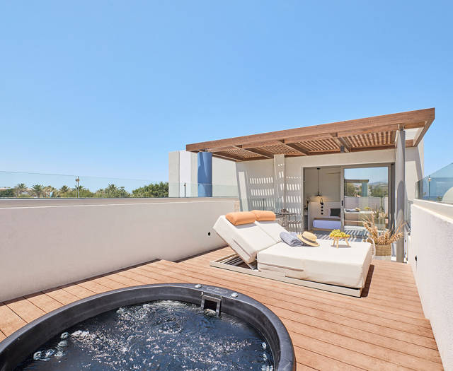 Rooftop terrace with hydromassage tub, sun loungers, and shaded lounge area under a wooden pergola.