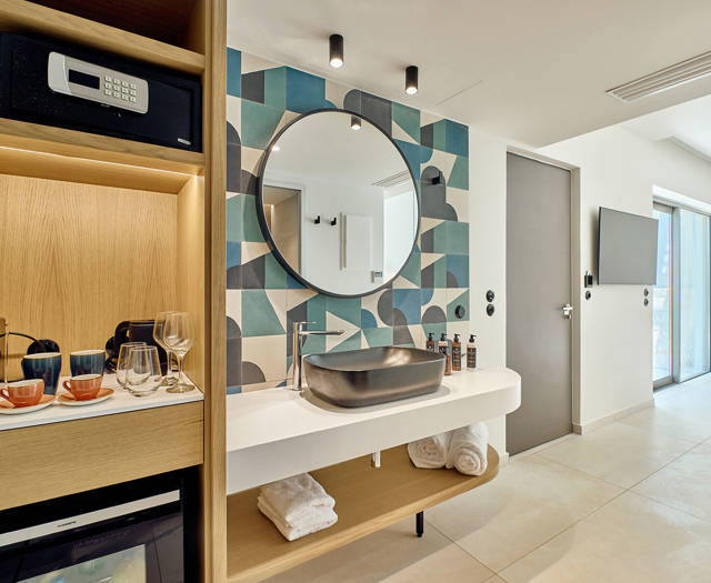 Bathroom vanity with designer sink, minibar setup, and view into the bedroom and poolside terrace.
