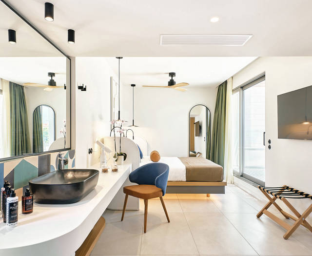 Open-plan rooftop room with modern bathroom, large mirrors, and natural light from balcony access.
