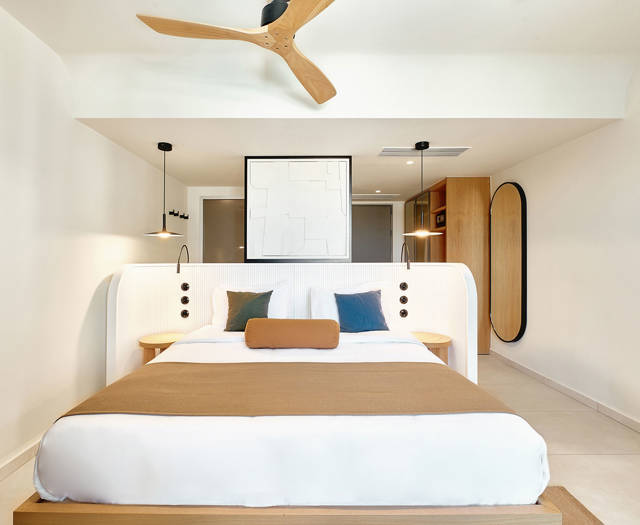 Modern double bed with soft linens, accent pillows, and warm ambient lighting.